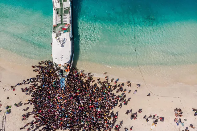 This handout aerial photo taken by Melissa Delport from @trufflejournal on August 6, 2018 and received on August 8 shows people crowding the beach as they wait to be evacuated from Gili Trawangan island to neighbouring Lombok island a day after a 6.9 magnitude earthquake struck the area. More than 70,000 people left homeless by a deadly earthquake on the Indonesian island of Lombok were sleeping in makeshift shelters and lack food, medicine and clean water, officials said on August 8. (Photo by Melissa Delport/AFP Photo)