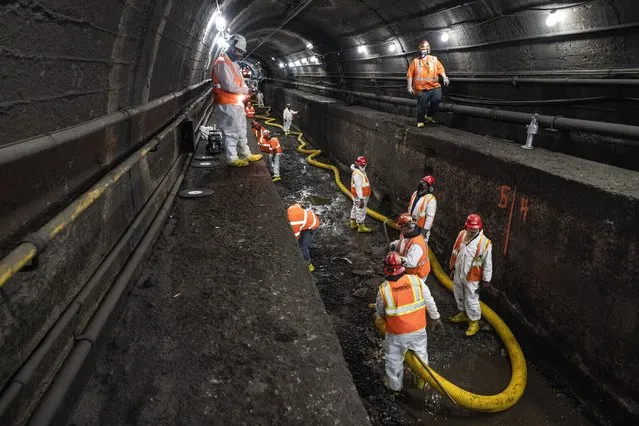 Amtrak workers perform tunnel repairs to a partially flooded train track bed, Saturday, March 20, 2021, in Weehawken, N.J. With a new rail tunnel into New York years away at best, Amtrak is embarking on an aggressive and expensive program to fix a 110-year-old tunnel in the interim. (Photo by John Minchillo/AP Photo)