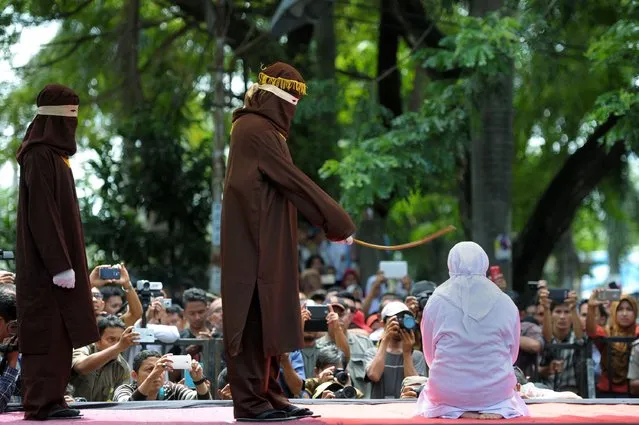 A religious officer canes an Acehnese woman (R) 100 times for having s*x outside marriage, which is against Sharia law, in Banda Aceh on November 28, 2016. (Photo by Chaideer Mahyuddin/AFP Photo)
