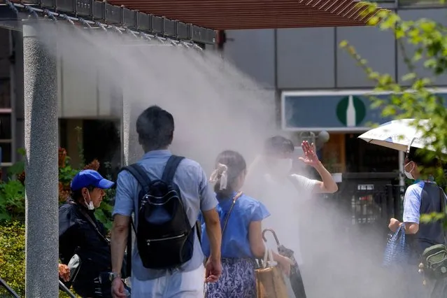 Pedestrians cool off in water mist during heatwave conditions in Tokyo on July 18, 2023. (Photo by Kazuhiro Nogi/AFP Photo)