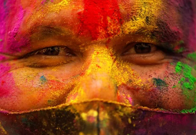 A man, with his face smeared in coloured powder, wears a protective face mask as he celebrates Holi in Kathmandu, Nepal on March 28, 2021. (Photo by Navesh Chitrakar/Reuters)