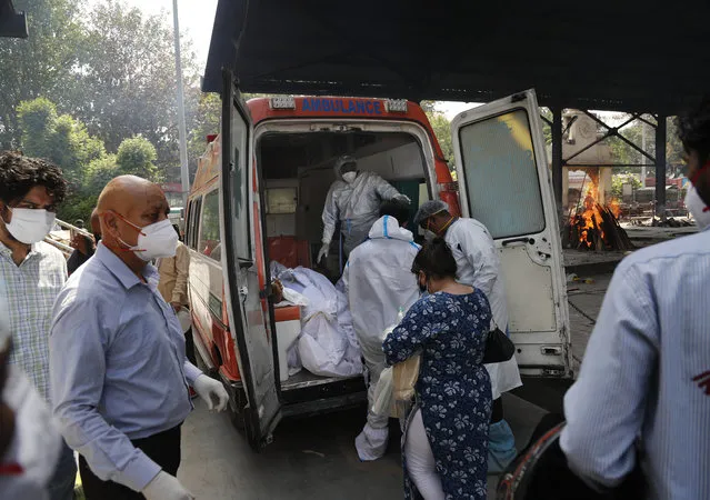 Health workers prepare to take out bodies of six victims of COVID-19 from an ambulance for cremation in New Delhi, India, Monday, April 19, 2021. India has been overwhelmed by hundreds of thousands of new coronavirus cases daily, bringing pain, fear and agony to many lives as lockdowns have been placed in Delhi and other cities around the country. (Photo by Manish Swarup/AP Photo)