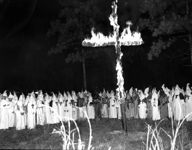 A fiery cross was burned by Ku Klux Klan members at a meeting at a suburban area in Jacksonville, Fla. on June 3, 1950.  Some of the Klan members lowered their masks while pictures were being taken. (Photo by AP Photo)