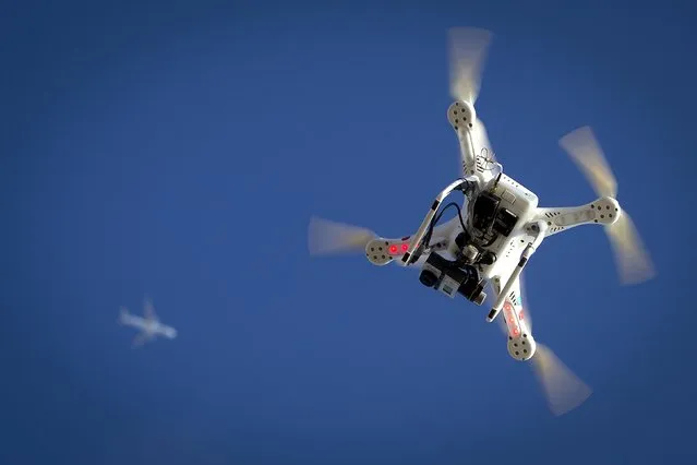 An airplane flies over a drone during the Polar Bear Plunge on Coney Island in the Brooklyn borough of New York in this file photo taken January 1, 2015. U.S. farmers hoping to use drones to locate lost livestock or monitor trouble spots in their fields were disappointed by what they say are overly restrictive commercial drone rules proposed February 15, 2015, by the Federal Aviation Administration. (Photo by Carlo Allegri/Reuters)