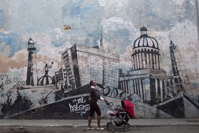 A woman pushes a stroller as she passes by a wall mural depicting Havana, in Havana, February 11, 2015. (Photo by Alexandre Meneghini/Reuters)