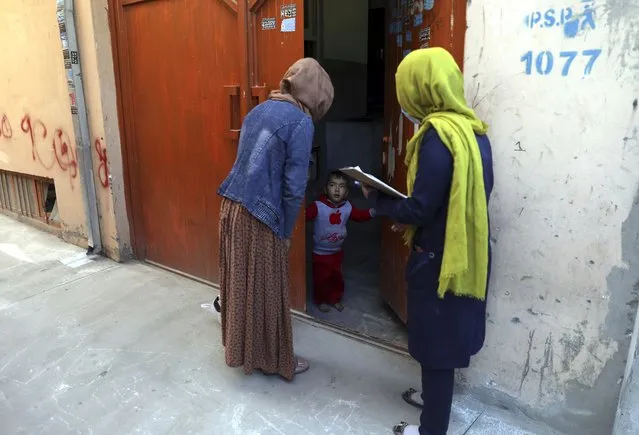 Health workers go door to door during a polio vaccination campaign in the city of Kabul, Afghanistan, Tuesday, March 30, 2021. Three female polio vaccinators were gunned down in separate attacks Tuesday in eastern Afghanistan, provincial officials said. (Photo by Rahmat Gul/AP Photo)