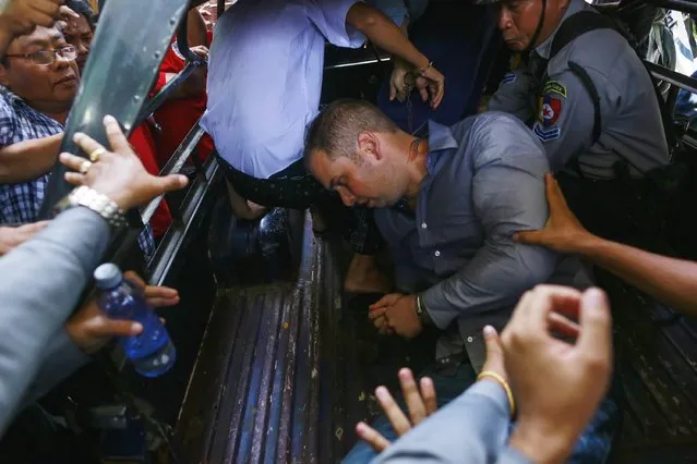 Phil Blackwood, a bar manager from New Zealand, falls into a police vehicle as he is taken way after being sentenced to two and half years in prison, at Bahan township court in Yangon, March 17, 2015. Blackwood was found guilty along with two Myanmar citizens, bar owner Tun Thurein and manager Htut Ko Ko Lwin, of insulting religion after publishing a psychedelic image of Buddha wearing headphones to promote his bar in Yangon. (Photo by Soe Zeya/Reuters)