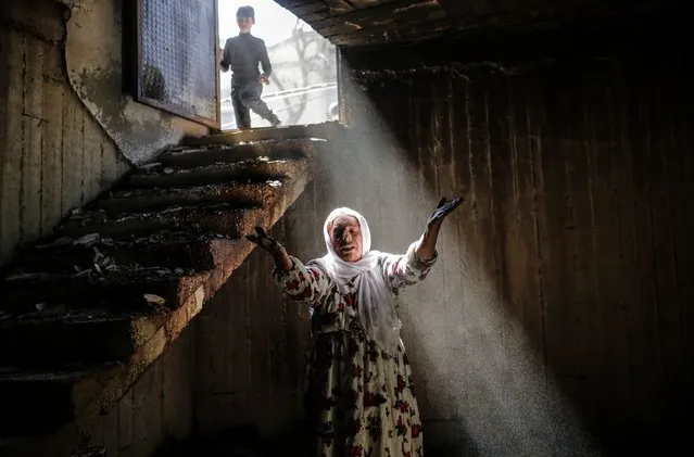 A woman reacts while walking among the ruins of damaged buildings following heavy fighting between government troops and Kurdish fighters, on March 2, 2016 in the southeastern Turkey Kurdish town of Cizre, near the border with Syria and Iraq. Thousands in Turkey's Kurdish-majority town of Cizre started returning to their homes today after authorities partially lifted a curfew in place since December for a controversial military operation to root out separatist rebels. (Photo by Yasin Akgul/AFP Photo)