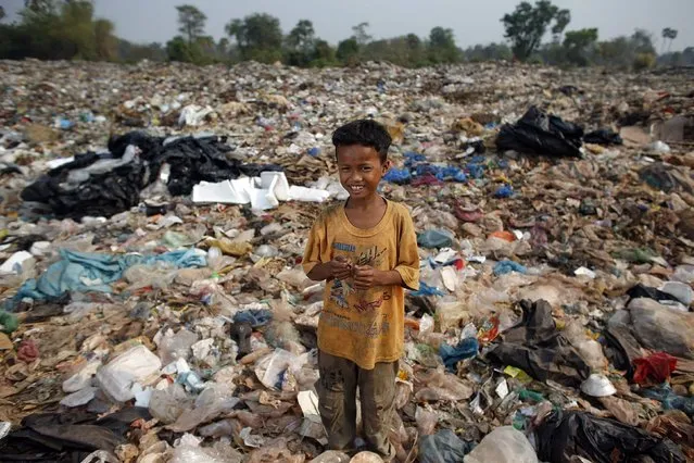 Ty, a 15-year-old boy, poses for a picture while collecting usable items at a landfill dumpsite outside Siem Reap March 19, 2015. Ty, who finished  six-grade primary school, said he makes 5 USD per month working at the dumpsite. (Photo by Athit Perawongmetha/Reuters)