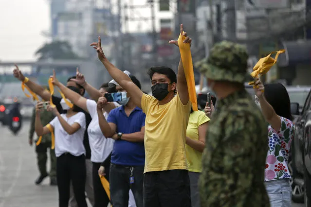 Supporters of former Philippine President Benigno Aquino III flash the “L” sign meaning “Fight!” during a motorcade before his burial in Quezon City, Philippines on Saturday, June 26, 2021. (Photo by Basilio Sepe/AP Photo)