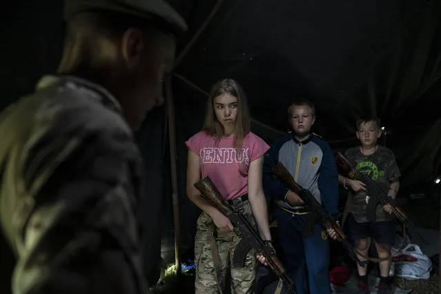 In this July 28, 2018 photo, participants of the “Temper of will” summer camp, organized by the nationalist Svoboda party, hold their AK-47 riffles as they receive instructions during a tactical exercise in a village near Ternopil, Ukraine. Campers as young as 8 years old practice using assault rifles. They are taught to shoot to kill Russians and their sympathizers. (Photo by Felipe Dana/AP Photo)