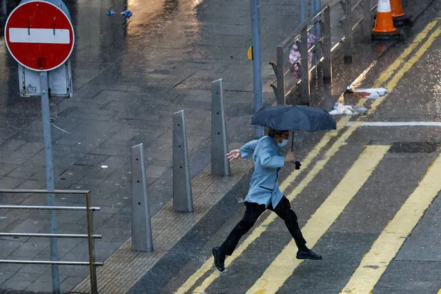 A man jumps past a puddle as Typhoon Koinu brings heavy rain to the city, in Hong Kong, China on October 9, 2023. (Photo by Tyrone Siu/Reuters)