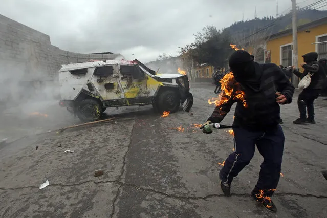 A demonstrator is engulfed in flames from a petrol bomb that was thrown at a police vehicle during protests marking the anniversary of the coup that toppled President Salvador Allende and brought dictator General Augusto Pinochet to power 49 years ago, in Santiago, Chile, Sunday, September 11, 2022. (Photo by Luis Hidalgo/AP Photo)