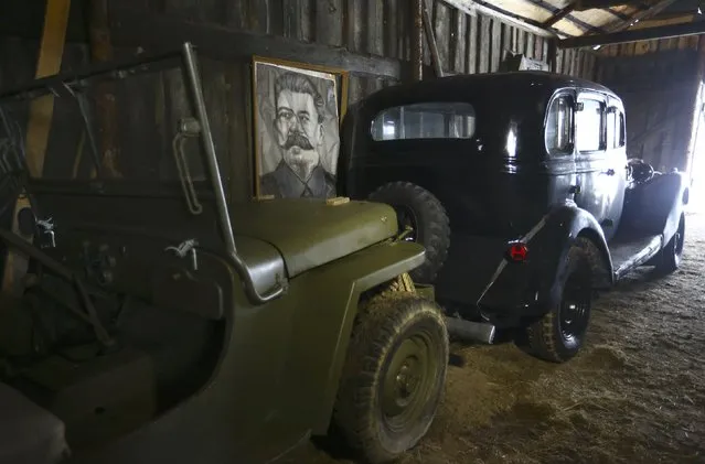 A portrait of Soviet dictator Josef Stalin is seen behind cars from the collection of Danila Tsitovich, who finds and restores old cars and motorcycles, at his base in the village of Zabroddzie, Belarus December 20, 2016. (Photo by Vasily Fedosenko/Reuters)