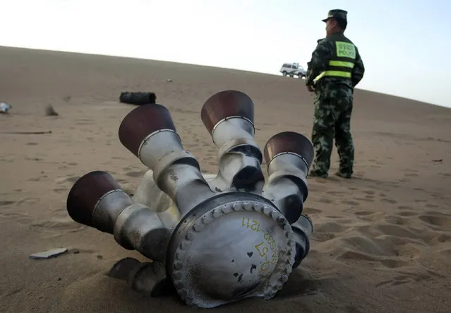 A policeman stands guard next to a component of the Shenzhou-10 manned spacecraft which was found in Badain Jaran Desert after the launch, in Alxa League, Inner Mongolia Autonomous Region June 12, 2013. (Photo by Reuters/China Stringer Network)