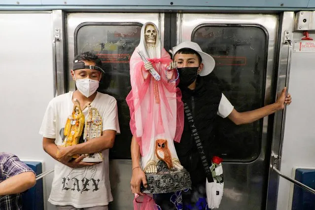 Two young men carry a figure of Santa Muerte inside a Mexico City metro carriage on August 1, 2021 during the COVID-19 health emergency in Mexico and the orange epidemiological traffic light in the capital. (Photo by Gerardo Vieyra/NurPhoto/Rex Features/Shutterstock)