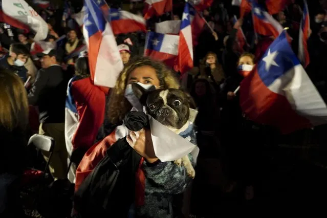 A demonstrator holds a dog during a rally against the proposed new Constitution in Santiago, Chile, Thursday, September 1, 2022. Chileans have until the Sept. 4 plebiscite to study the new draft and decide if it will replace the current Magna Carta imposed by a military dictatorship 41 years ago. (Photo by Matias Basualdo/AP Photo)