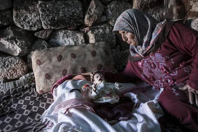 In this Friday, September 27, 2013 photo, a displaced Syrian woman comforts her one-month old grandchild Fatima inside a stone house near Kafer Rouma, in ancient ruins used as temporary shelter by those families who have fled from the heavy fighting and shelling in the Idlib province countryside of Syria. (Photo by Narciso Contreras/AP Photo)
