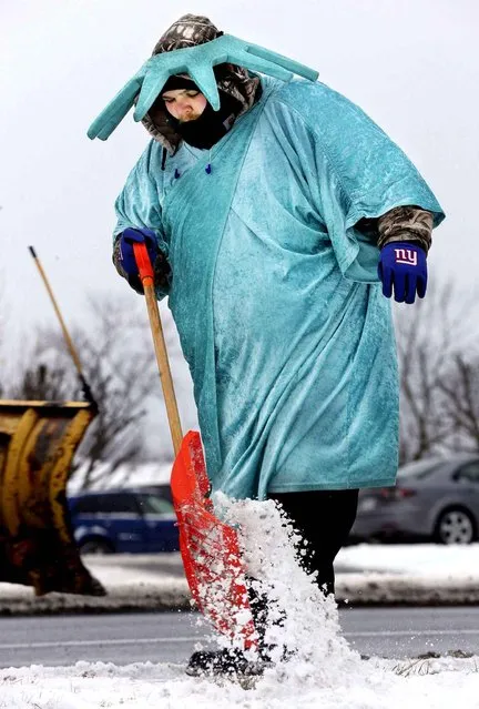 Michael Pellot shovels snow while wearing a Statue of Liberty costume in front of Liberty Tax Service's Winchester, Va., offices Monday, February 15, 2016. Liberty employs people to dress in the Statue of Liberty outfits to attract potential customers' attention. (Photo by Scott Mason/The Winchester Star via AP Photo)