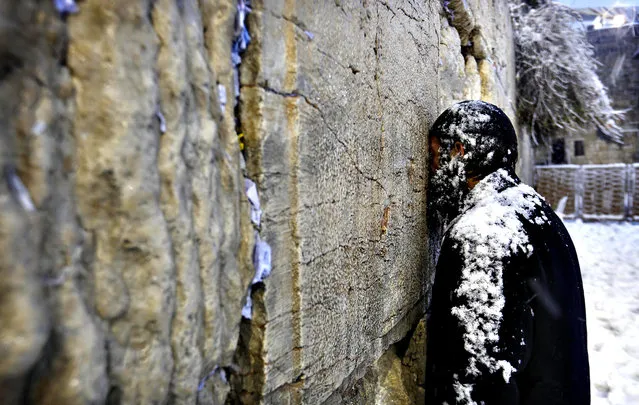 An Ultra-Orthodox Jewish man prays at  the Western Wall in Jerusalem's Old City during a snowstorm December 13, 2013. (Photo by Darren Whiteside/Reuters)