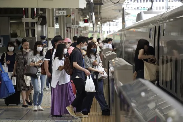 In this July 31, 2021, file photo, passengers wearing face masks to help curb the spread of the coronavirus get on board a west-bound bullet train at Tokyo Station in Tokyo. Outside the Olympic bubble, fueled by the more contagious delta variant, infections in Tokyo have logged new daily records and nearly tripled in the first week after the Games opened on July 23. Japanese officials say the surge is unrelated to the Olympics. (Photo by Kantaro Komiya/AP Photo/File)