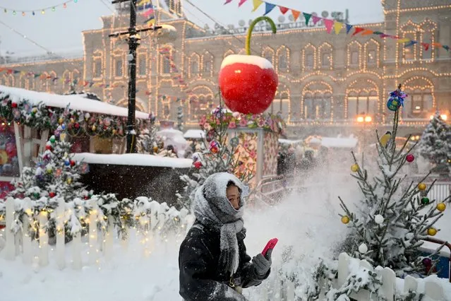A woman walks past Christmas market stalls in the snow-covered Red Square in Moscow on December 3, 2023. (Photo by Alexey Pavlovsky/AFP Photo)