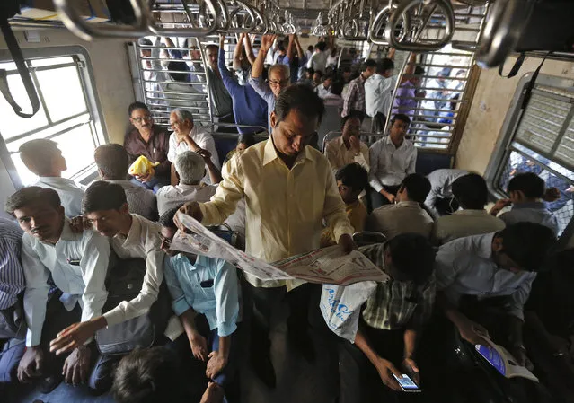 A man reads the newspaper as he commutes to work by a local train in Mumbai, February 25, 2015. (Photo by Shailesh Andrade/Reuters)