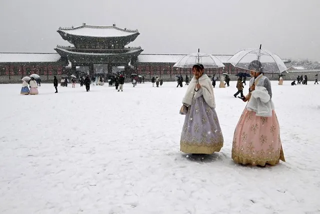 Visitors wearing traditional hanbok dress walk in the snow at Gyeongbokgung palace in central Seoul on December 30, 2023. (Photo by Jung Yeon-je/AFP Photo)