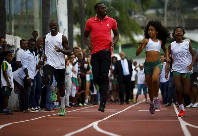 Jamaican Olympic gold medallist Usain Bolt (C) runs with youths at Mangueira slum Olympic center, ahead of the “Mano a Mano” challenge, a 100-meter race which will be held on this Sunday, in Rio de Janeiro April 16, 2015. (Photo by Ricardo Moraes/Reuters)