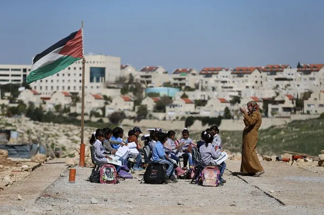 A teacher gives a class to Palestinian bedouin students outdoors near the Jewish settlement of Maale Adumim (seen in the background), in the West Bank village of Al-Eizariya, east of Jerusalem March 1, 2016. The Israeli forces dismantled the caravans that were used as classrooms for the Beduin community school on February 20, residents said. According to school officials, the Israeli army informed them that the containers were removed because they did not have an Israeli-issued construction permit to stay in the area. (Photo by Ammar Awad/Reuters)