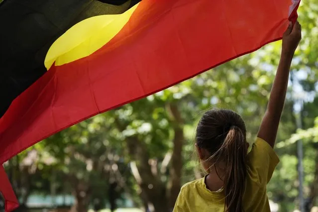A young girl holds an Aboriginal flag at an Indigenous Australians protest during Australia Day in Sydney, Friday, January 26, 2024. Thousands of Australians protest on the anniversary of British colonization of their country amid fierce debate over whether the increasingly polarizing national holiday dubbed “Australia Day” should be moved to another date. (Photo by Rick Rycroft/AP Photo)