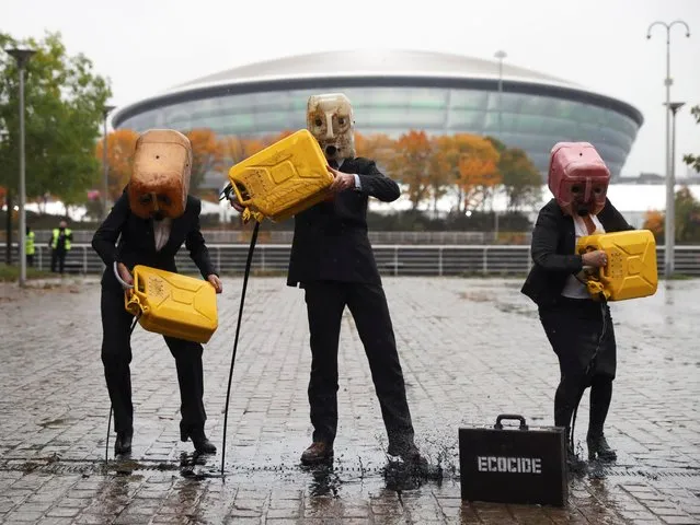 Ocean Rebellion activists wear oil canister masks as they spill fake oil in front of the venue for COP26 in Glasgow, Scotland, Britain, October 29, 2021. (Photo by Russell Cheyne/Reuters)