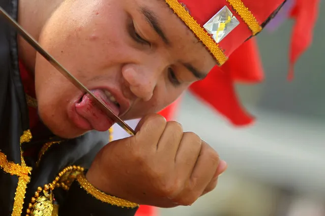 A worshipper cuts his tongue as he takes part in Hei Neak Ta, or procession of the spirits which marks the end of the celebration of the Lunar New Year for the Chinese community in Phnom Penh, Cambodia, February 10, 2017. (Photo by Samrang Pring/Reuters)