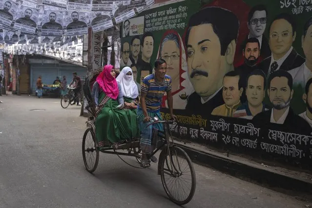 A rickshaw ferrying passengers rides past a mural displaying portraits of Bangladesh Prime Minister Sheikh Hasina, her father and founder of the nation Sheikh Mujibur Rahman and other leaders in Dhaka, Bangladesh, Friday, January 5, 2024. (Photo by Altaf Qadri/AP Photo)