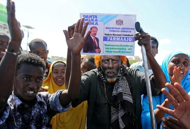 A man carries a poster with the image of the newly elected Somalian President Mohamed Abdullahi Mohamed as he and others celebrate his victory, near the Daljirka Dahson monument in Mogadishu, Somalia February 11, 2017. (Photo by Feisal Omar/Reuters)