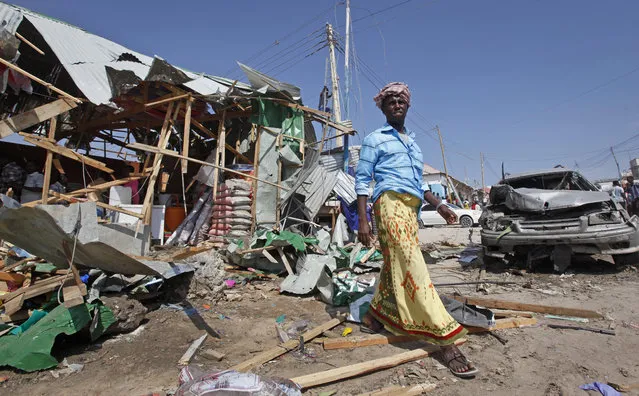 A man walks past the wreckage of shops destroyed by a blast in a market in the capital Mogadishu, Somalia, Sunday, February 19, 2017. A Somali police officer says a blast at a busy market in the western part of Somalia's capital tore through shops and food stands and killed more than a dozen people and wounded many others. (Photo by Farah Abdi Warsameh/AP Photo)