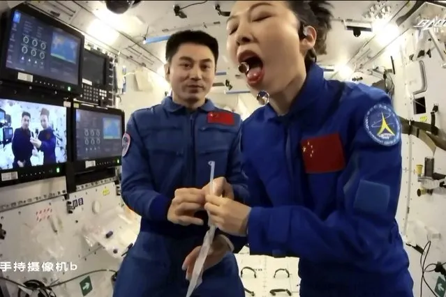 In this image taken from video footage run by China's CCTV, astronaut Wang Yaping, right, demonstrates how to consume water in zero gravity during a lesson for Chinese children through video link from the China's space station orbiting earth on Thursday, December 9, 2021. (Photo by CCTV via AP Photo)