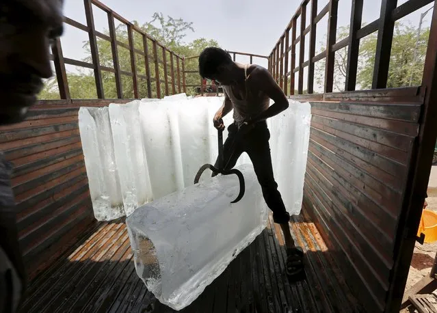 The worker of an ice factory loads an ice bar onto a truck to supply to a market on a hot summer day on the outskirts of Ahmedabad, India, May 19, 2015. Temperatures in Ahmedabad on Tuesday reached 44 degrees Celsius (111.2 degrees Fahrenheit), according to India's meteorological department website. (Photo by Amit Dave/Reuters)