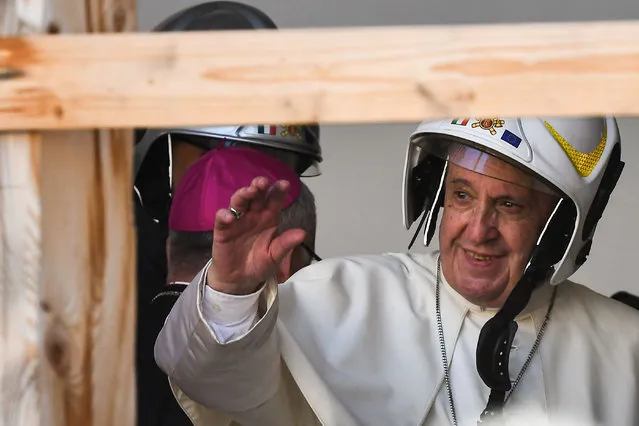 Pope Francis, wearing a safety helmet, waves as he prepares to enter the cathedral of Camerino as part of a visit on June 16, 2019 to the areas affected by the August 24, 2016 earthquake in the diocese of Camerino-San Severino Marche. (Photo by Vincenzo Pinto/AFP Photo)