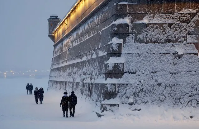 People walk along the wall of the Peter&Paul fortress during a snowfall in St. Petersburg, Russia, 09 January 2022. The temperatures have reached below three degrees Celsius in the second largest city of Russia. (Photo by Anatoly Maltsev/EPA/EFE)