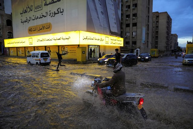 A man rides a motorcycle on a flooded street following heavy rains in Sanaa, Yemen on April 22, 2024. (Photo by Khaled Abdullah/Reuters)