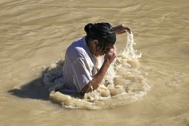A Orthodox Christian pilgrim immerses himself in the Jordan River during a baptism ceremony as part of the Orthodox Feast of the Epiphany at Qasr el Yahud, near the West Bank town of Jericho, Tuesday, January 18, 2022. The site is traditionally believed by many to be the place where Jesus was baptized. (Photo by Mahmoud Illean/AP Photo)