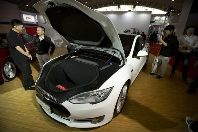 Visitors gather around a Tesla Model S electric car on display at the Beijing International Automotive Exhibition in Beijing, Monday, April 25, 2016. (Photo by Mark Schiefelbein/AP Photo)