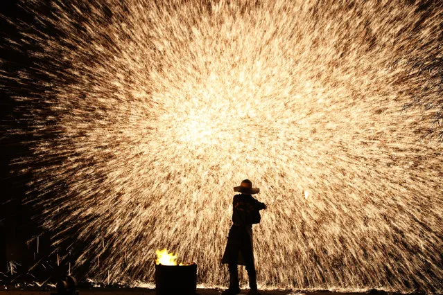 A folk artist performs molten iron fireworks at Hengnan County on July 17, 2019 in Hengyang, Hunan Province of China. (Photo by VCG/VCG via Getty Images)