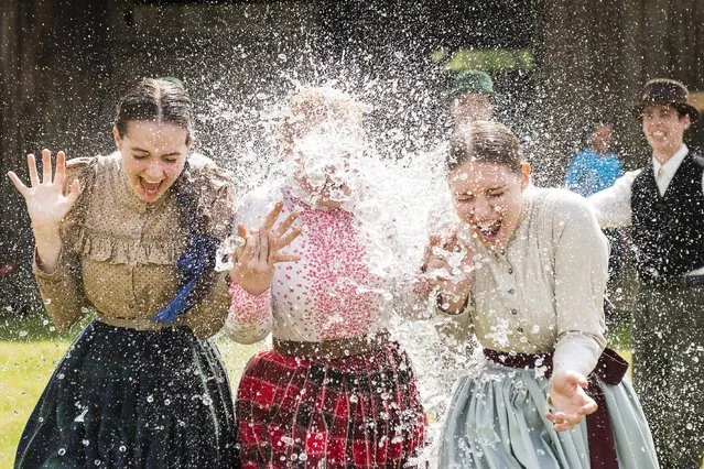 Women in traditional costumes are sprayed with water by men as members of the Marghareta Dance Group perform Easter folk traditions of the region in the Museum Village in Nyiregyhaza, 227 kms northeast of Budapest, Hungary, Monday, April 21, 2014. According to a hundred years old tradition of Hungarian villages, young men pour water on young women who in exchange present their sprinklers with beautifully coloured eggs on Easter Monday. (Photo by Attila Balazs/AP Photo/MTI)