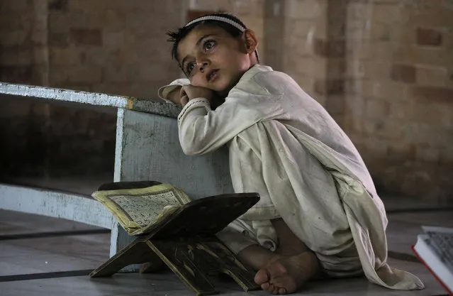 A Pakistani child takes a break during a class to learn the Quran at a mosque in Peshawar, Pakistan, Friday, July 3, 2015. Muslims across the world are observing the holy fasting month of Ramadan, where they refrain from eating, drinking and smoking from dawn to dusk. (Photo by Mohammad Sajjad/AP Photo)