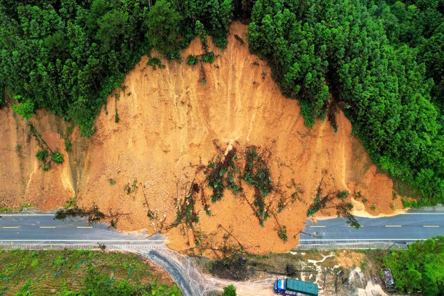 This aerial photo shows a truck driving past a landslide site after storms in Liuzhou, in southwestern China's Guangxi province on June 13, 2024. (Photo by AFP Photo/China Stringer Network)