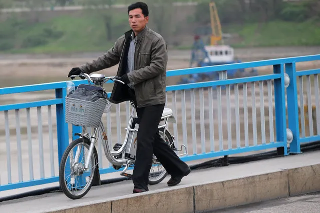 A man pushes an electric bicycle over the bridge in Pyongyang, North Korea May 6, 2016. (Photo by Damir Sagolj/Reuters)