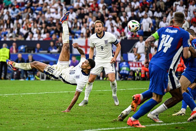 England's midfielder #10 Jude Bellingham (L) shoots an overhead kick to score his team's first goal during the UEFA Euro 2024 round of 16 football match between England and Slovakia at the Arena AufSchalke in Gelsenkirchen on June 30, 2024. (Photo by Ina Fassbender/AFP Photo)