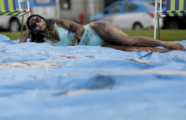 A demonstrator painted with fake oil lies on a tarp during a protest against the auction for the exploration of oil fields close to Abrolhos, a marine national park in Bahia state, in front of the Grand Hyatt Hotel where the auction is taking place, in Rio de Janeiro, Brazil, Thursday, October 10, 2019. Under pressure from environmental organizations, none of the 17 companies involved in the process presented any offers. (Photo by Silvia Izquierdo/AP Photo)